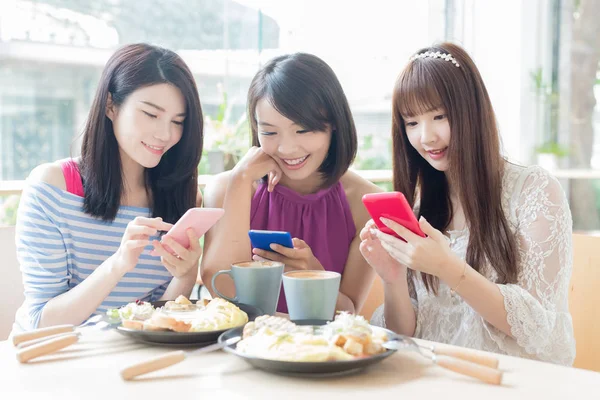happy women friends using  phones in restaurant
