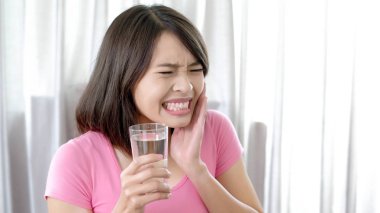 woman holding   water  with toothache at  home clipart
