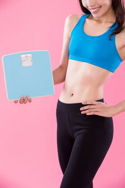 ピンク色の背景に体重計を保持しているスポーツの女性 — ストック写真