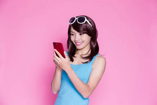 ピンク色の背景に携帯電話を使用してのサングラスをかけた女性 — ストック写真