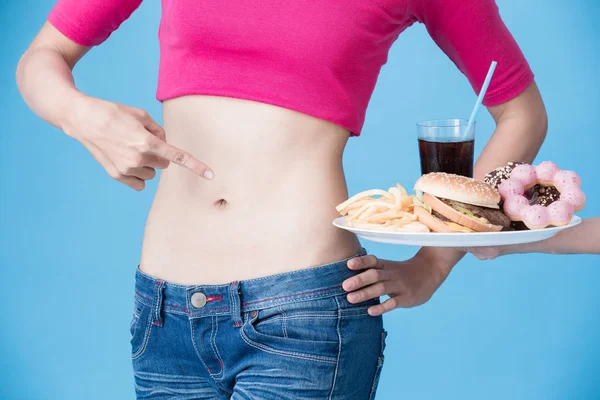 Женщине Предлагают Нездоровую Пищу Синем Фоне — стоковое фото