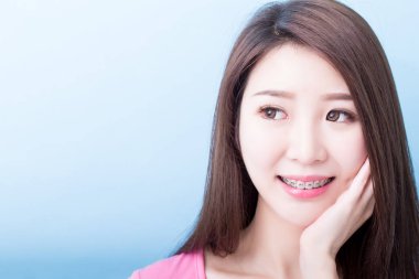 woman wearing  braces and  looking  somewhere  on the blue background clipart
