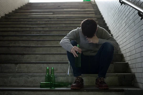 アルコール依存症問題が地下に座っていると落ち込んでいる男 — ストック写真