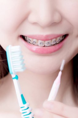 woman wearing braces and holding  different brushes clipart