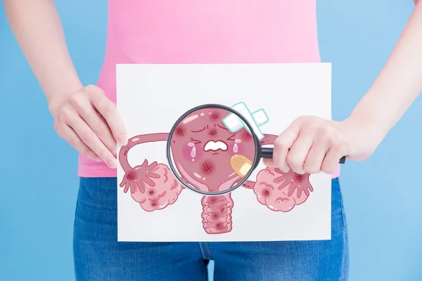 子宮の看板と青い背景に虫眼鏡を持つ女性 — ストック写真