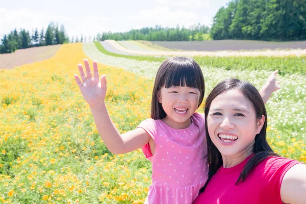 mother and daughter taking selfie and smiling  happily with beautiful landscape in furano