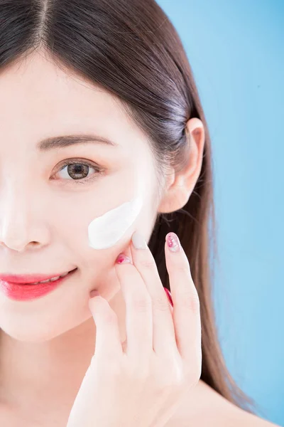 Mujer Aplicando Crema Cara Con Fondo Azul — Foto de Stock