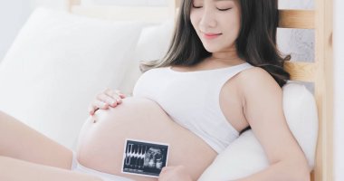 pregnant woman holding baby ultrasound picture on the bed clipart