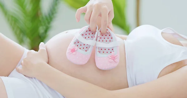 Mulher Grávida Segurando Pequenos Sapatos Bebê Deitado Cama — Fotografia de Stock