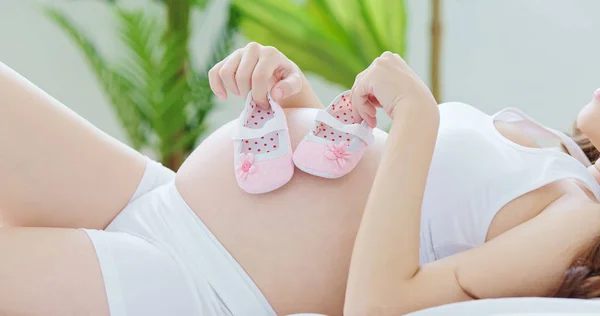 Pregnant Woman Holding Small Baby Shoes Lying Bed — Stock Photo, Image