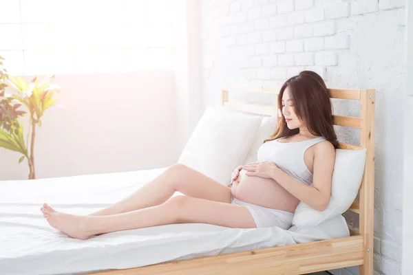 自宅でベッドの上に座って妊娠中の女性 — ストック写真