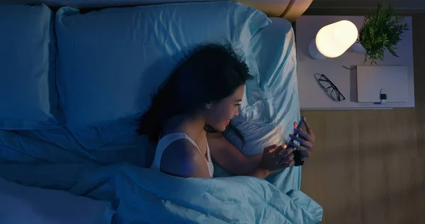 Kvinna använder smartphone på sängen — Stockfoto