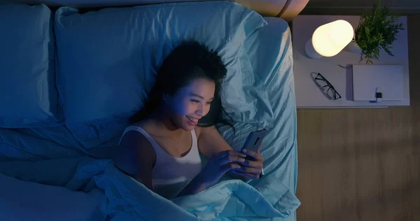 Kvinna använder smartphone på sängen — Stockfoto