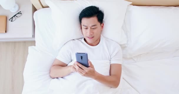 Hombre uso smartphone en la cama — Vídeos de Stock