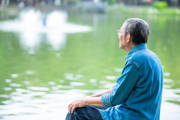 Älterer Mann sitzt in der Nähe des Sees — Stockfoto