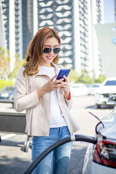 Vrouw opladen elektrische auto — Stockfoto