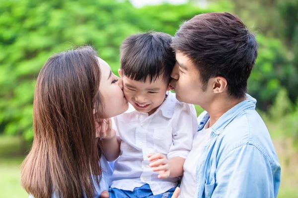 Junge Eltern küssen ihr Kind — Stockfoto