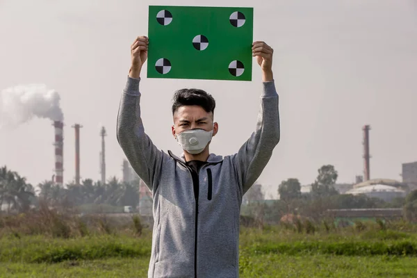 亚洲人拿着绿色的太空广告牌 头戴95号防护面罩 站在工厂前防止空气污染 — 图库照片