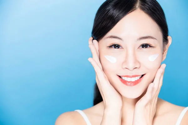 アジアの美人は化粧水や日焼け止めを顔に塗り笑顔で — ストック写真