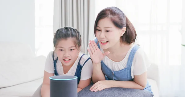 Smart AI speaker concept - Mom and daughter talk to voice assistant at home and feel happy