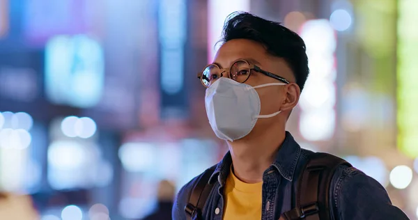 Asian man wears protective mask to prevent transmissible infectious diseases or air pollution in the city at night