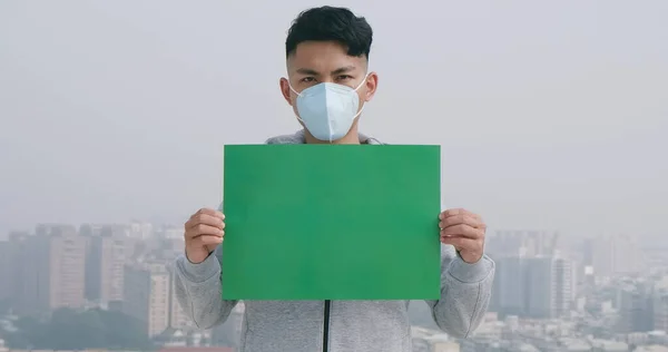 亚洲人拿着绿色的太空广告牌 戴着防护面具 防止城市里的传染性传染病或空气污染 — 图库照片