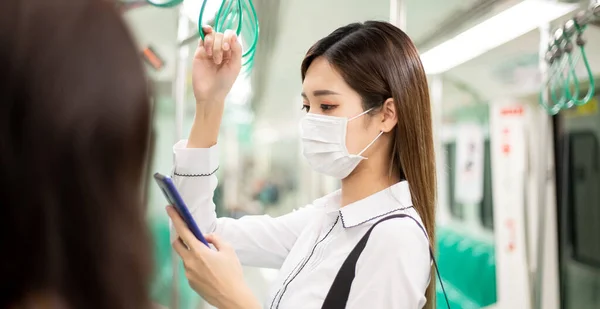 아시아인 사업가는 지하철이나 기차에서 통근하는 수술용 마스크를 스마트폰을 — 스톡 사진
