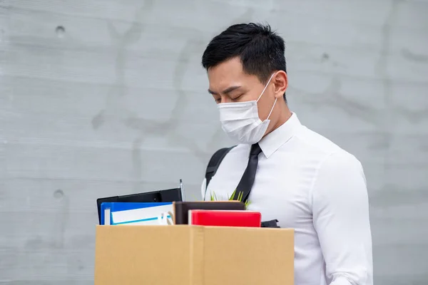 アジアのビジネスマンは顔のマスクを着用し 彼は世界中のCovid 19スプレッドの経済の低迷のために解雇されています — ストック写真