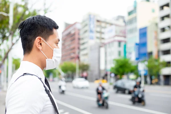 アジアのビジネスマンは都市で外科マスクの顔の保護を持つ何かを見てまたは考える — ストック写真