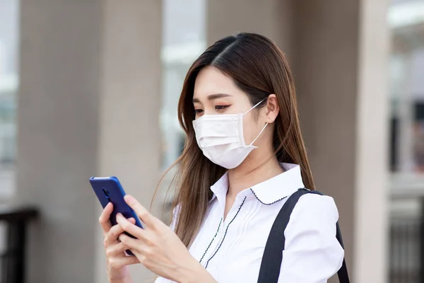 Asiatisk Kvinne Med Operasjonsmaske Ansiktsbeskyttelse Hun Bruker Smarttelefon Mens Hun – stockfoto