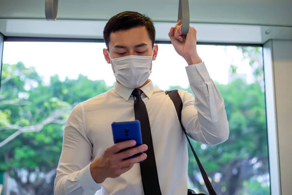 Asiatischer Geschäftsmann Nutzt Smartphone Mit Mundschutz Beim Pendeln Bahn Oder — Stockfoto