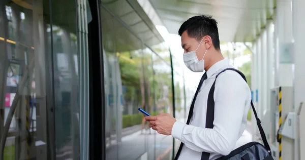 アジアのビジネスマンは 外科用マスク顔保護とスマートフォンを使用し 地下鉄や鉄道駅で待っている間 社会的距離を保ちます — ストック写真