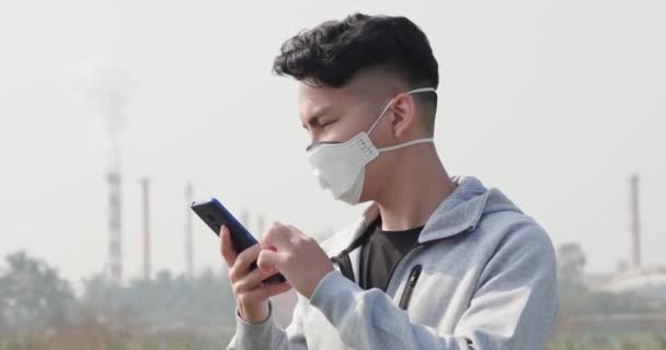 Мужчина пользуется смартфоном с маской — стоковое видео