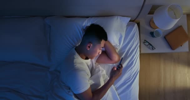 Мужчина пользуется смартфоном на кровати — стоковое видео