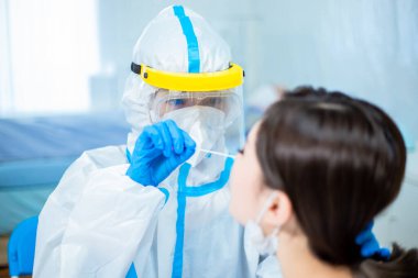 Coronavirus test - Medical worker taking a swab for corona virus sample from potentially infected woman with the isolation gown or protective suits and surgical face masks clipart