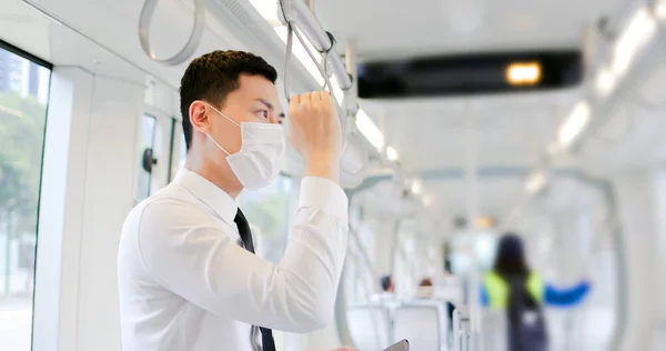 Asian business man with surgical mask face protection and keep social distancing while commuting in the metro or train