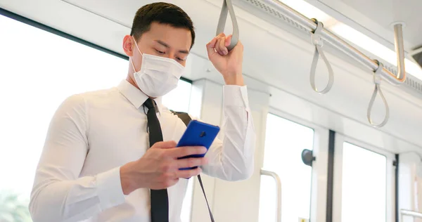 アジアのビジネスマンは 外科用マスク顔保護とスマートフォンを使用し 地下鉄や電車に通勤しながら 社会的距離を保ちます — ストック写真