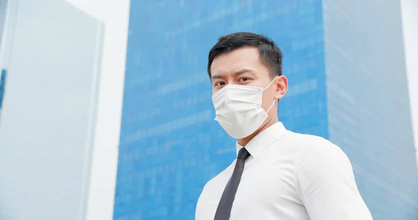 外科用フェイスマスクをしたアジア人のビジネスマンオフィスビルの前であなたを見てる — ストック写真