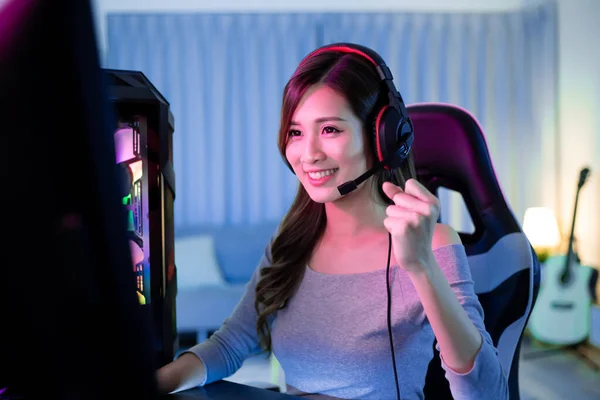 Young Asian Pretty Pro Gamer win in Online Video Game and cheer with hand up at home