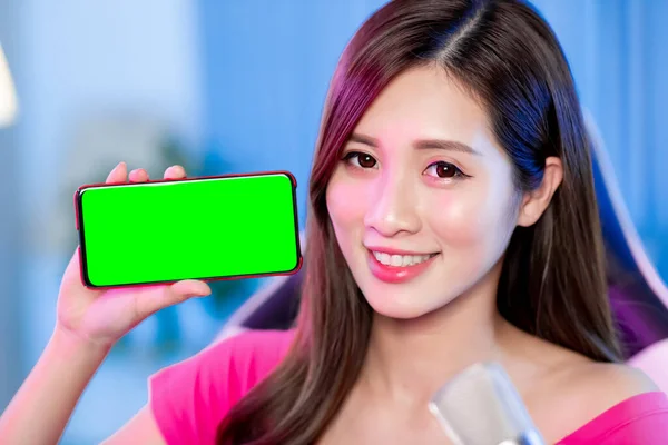 アジアの女の子のインターネット有名人は自宅で緑の画面で5Gのスマートフォン上のライブストリームとショーアプリを持っています — ストック写真