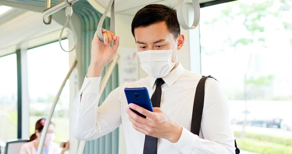 アジアのビジネスマンは 外科用マスク顔保護とスマートフォンを使用し 地下鉄や電車に通勤しながら 社会的距離を保ちます — ストック写真
