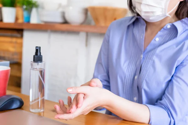 woman wipes hands with alcohol spray in order to kill virus prevent the spread of coronavirus with surgical face mask