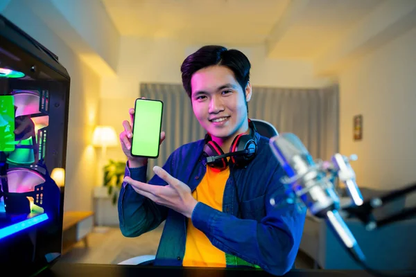 asian man internet celebrity have a live stream and show app on the smartphone with green screen at home