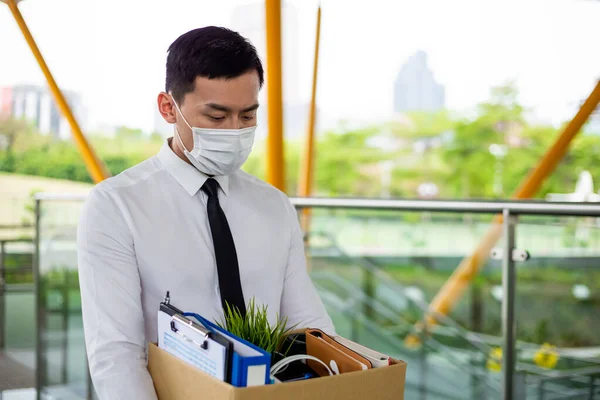 アジアのビジネスマンは顔のマスクを着用し 彼は世界中に広がるコロナウイルスによる経済的低迷のために解雇されています — ストック写真