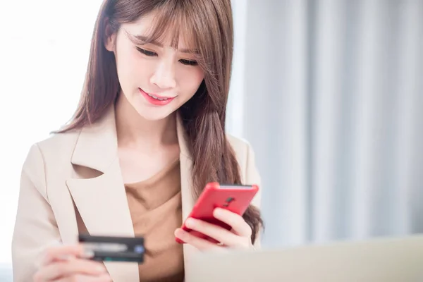 asian woman shopping on the internet and pay bill by credit card with smartphone at home