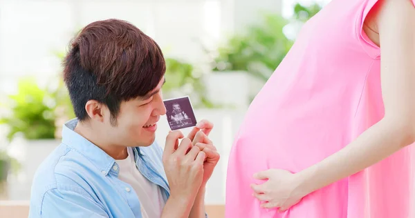 超音波写真を持って赤ちゃんと話す幸せな妊娠中のカップル — ストック写真