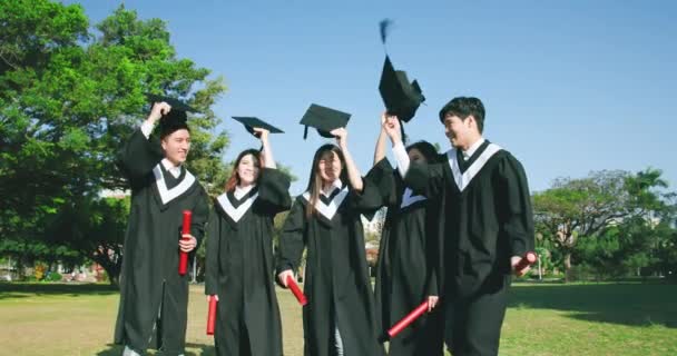 Groep gelukkig afgestudeerden gooien caps — Stockvideo