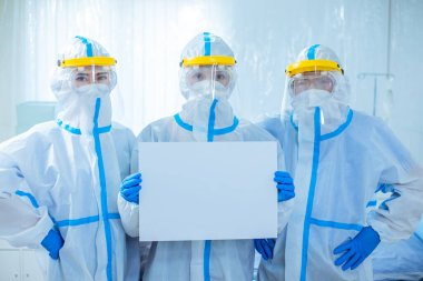 health workers look to you and show blank billboard - they wear the isolation gown or protective suits and surgical face masks in the control area to prevent the spread of coronavirus clipart