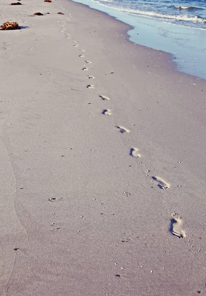 Voetafdrukken op het zand van een eenzaam strand — Stockfoto