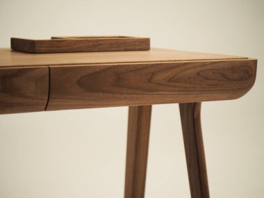 Doğal ahşaptan yapılmış şık bir masanın parçası. Üzerinde dizüstü bilgisayar ve çekmece olan masa üstü.